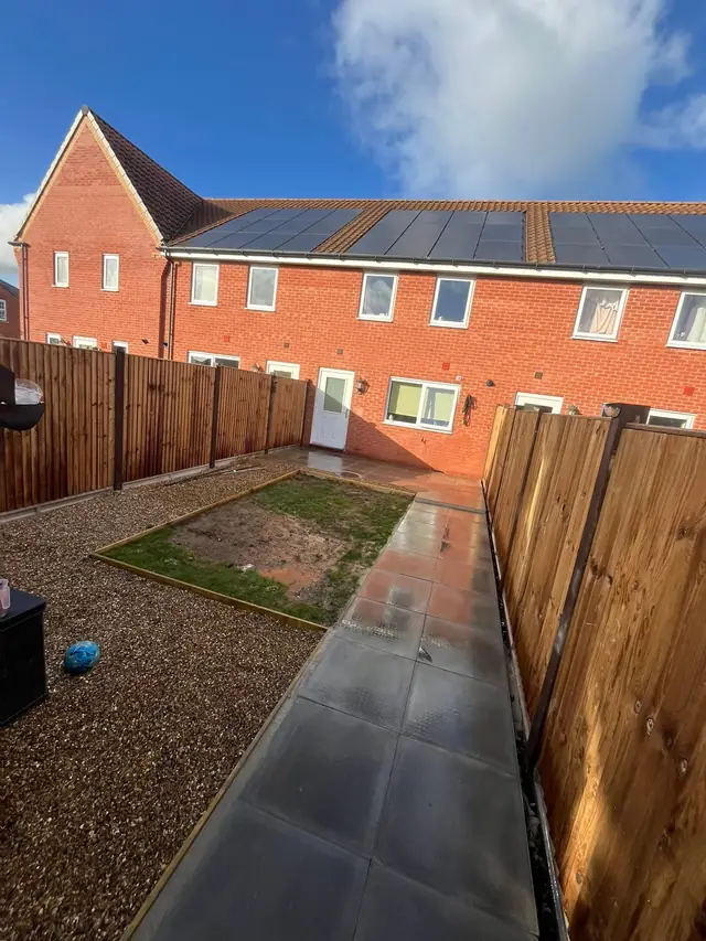 Back garden with new closeboard fencing, a paved path, gravel border and an area edged ready for turf